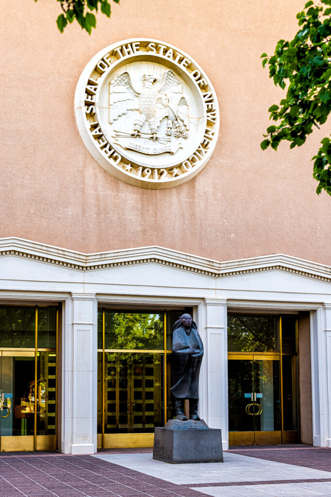 Santa Fe, USA - June 14, 2019: Capitol building in downtown center of city with entrance sign seal and statue by doors and nobody